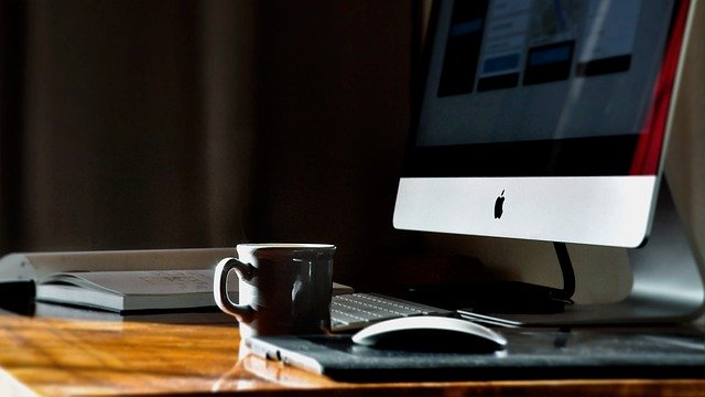 Coffee cup on a desk beside a computer monitor in a home office