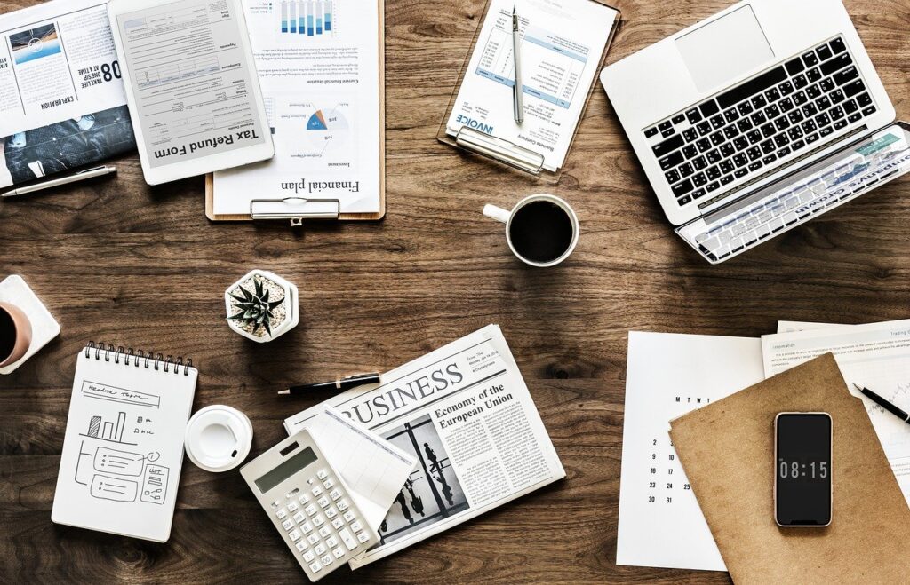 Desk with business documents, a laptop, a smartphone, and financial charts, symbolizing IT services and strategic business planning.